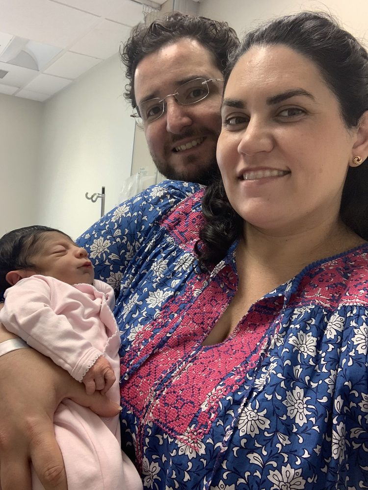 Katia and Luis smiling as they hold newborn Jemma