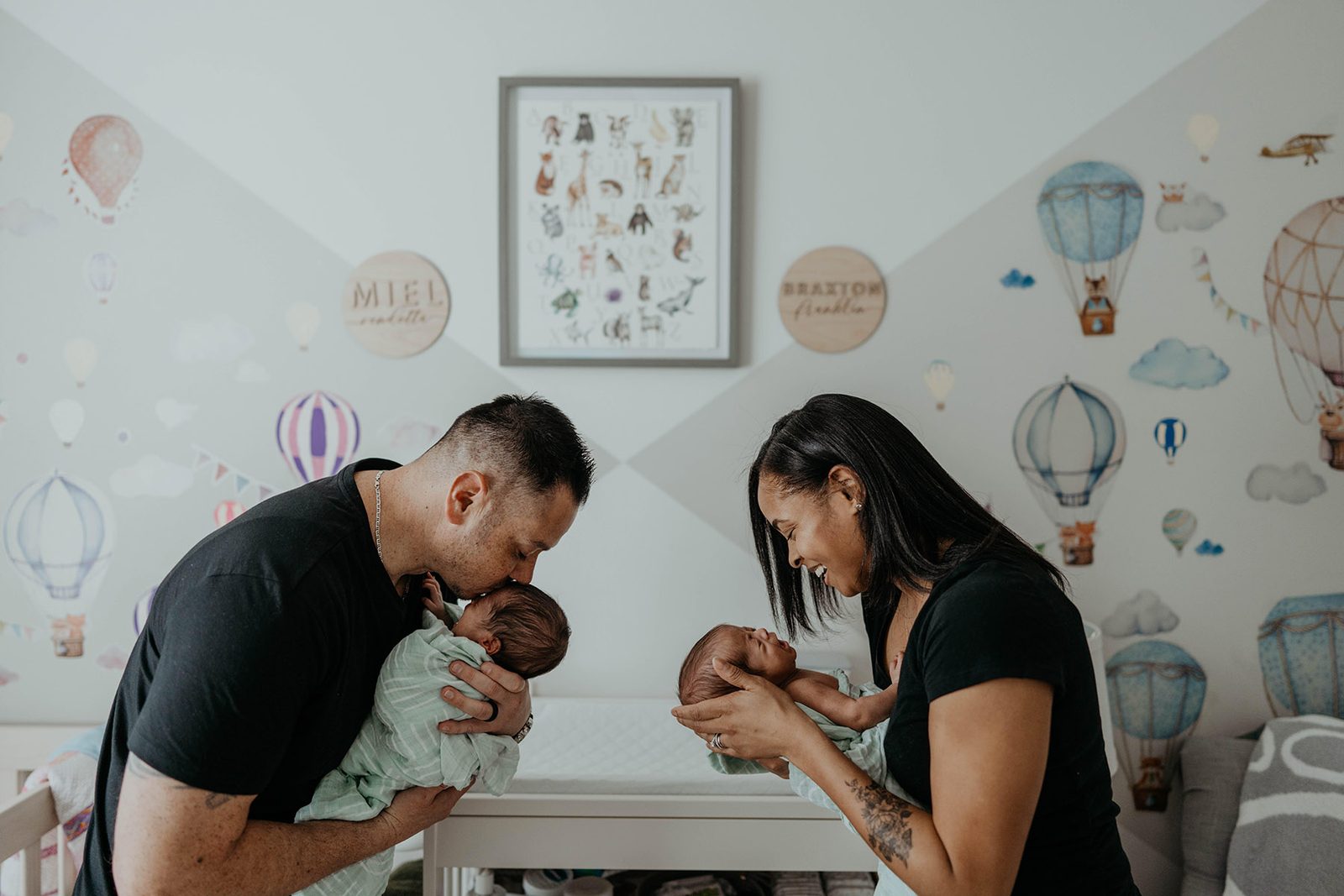 Denise and Troy each cradling one of their newborn twins in the nursery