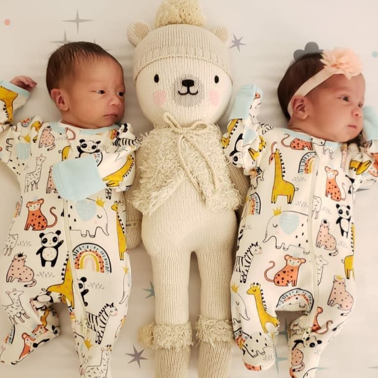 The twins lying on either side of a knitted teddy bear
